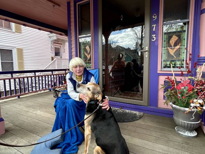 Barbara Filion enjoys a quiet morning on her front porch in Portsmouth with her neighbor's dog Buddy.