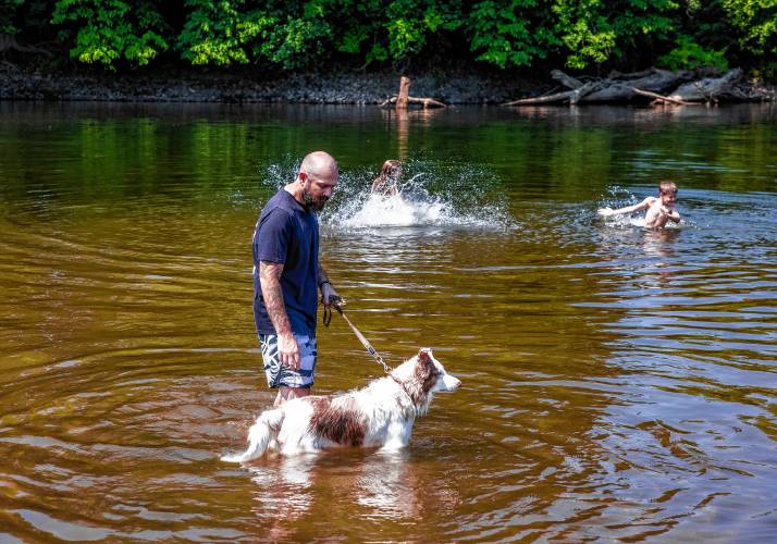 Nathan Lamere and his dog Dexter keep an eye on his son, Jonathan, and daughter Nateleigh, as they wade in the Merrimack River at Riverland Beach in Canterbury on Tuesday, June 18, 2024 as the tempertures started to rise in the area.