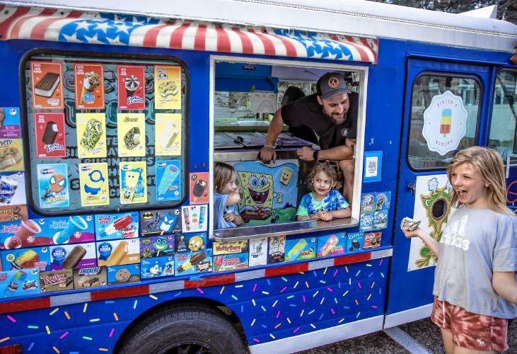 Paislee Bateman gets ready to order her ice cream from Adam Gelinas as his children, Avery (left) and Maisie chip in to help on Thursday, August 22, 2024. Bateman braved a rain shower to get her cone.