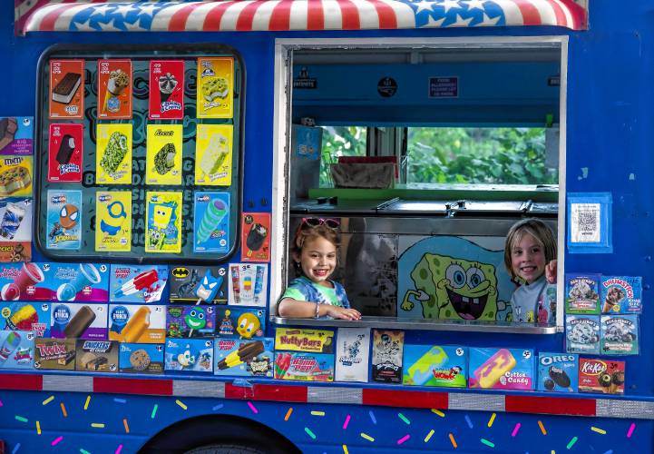 Maisie (left), and Avery help serve up ice cream from their van in the neighborhood near where they live in Allenstown on Thursday.