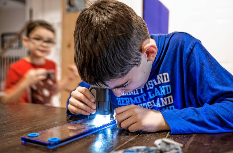 Bryce LeGeyt looks at a slide with tiny sea creatures through a mini microscope in the family living room on January 9, 2025.