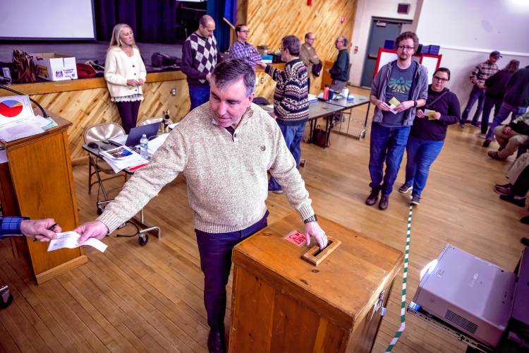 Pembroke town moderator Tom Serafin receives votes as residents cast their ballot on the first warrant article on Saturday.