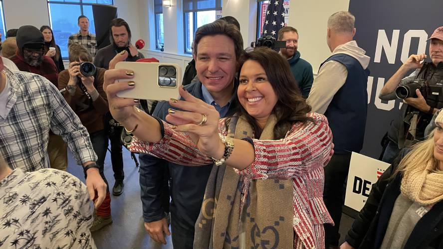 Ron DeSantis takes a photo with a supporter in Ankeny, Iowa.