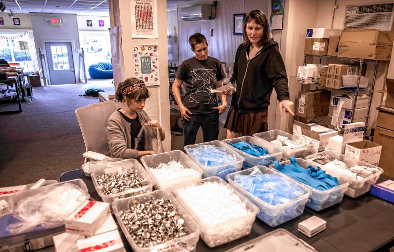 Palana Belken, right, shows volunteer Kat Legier, left, and Sparrow how to pack the kits to stock the van.