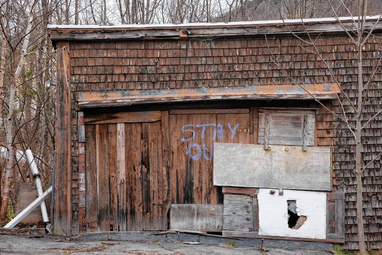  Rotten wood frames a broken window along the side of the property on Western Ave. in Berlin. Someone sprayed painted letters on the garage read ‘stay out.’