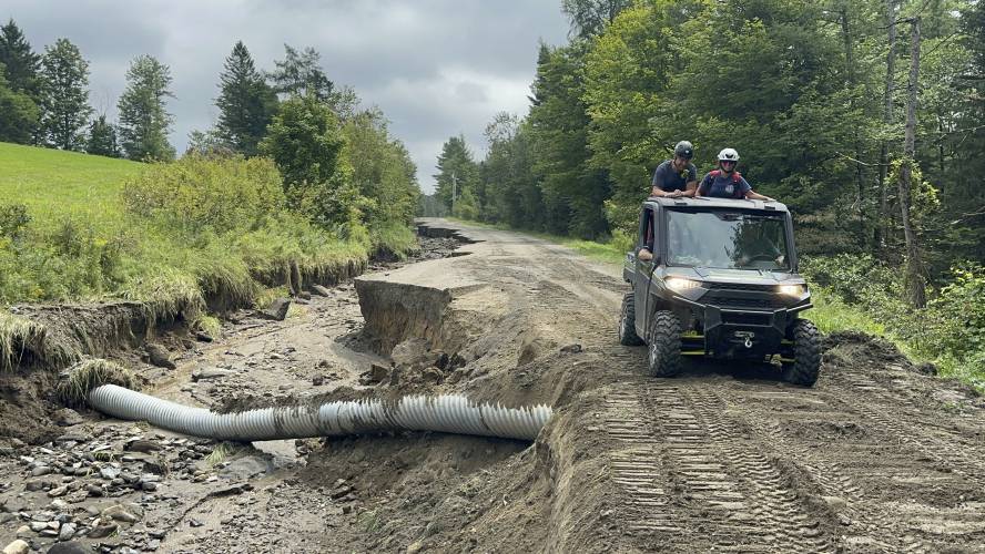 An all-terrain vehicle drives along a damaged roadway after flooding in Lyndonville, Vt., Tuesday, July 30, 2024. (AP Photo/Nick Perry)