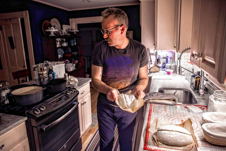 Alex Brown gets ready to put the dough for his bread into the oven at his South End home. Brown is getting a new bread oven to increase his weekly output.