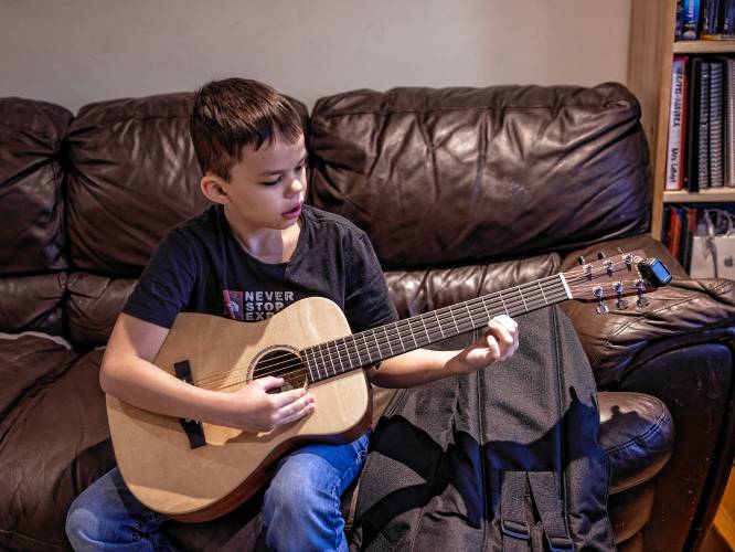 Ryan LeGeyt plays the guitar in the family living room in Concord on January 9, 2025.
