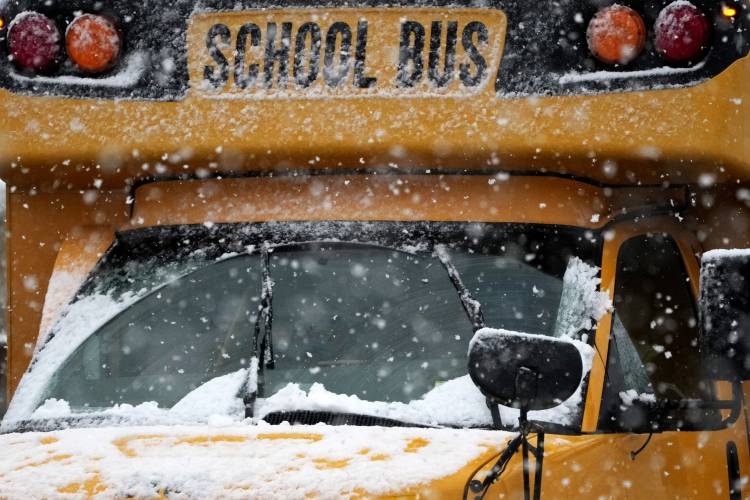 A school bus is driven along a snow-covered street during a heavy snow day in Wheeling, Ill., Tuesday, Jan. 9, 2024. (AP Photo/Nam Y. Huh)