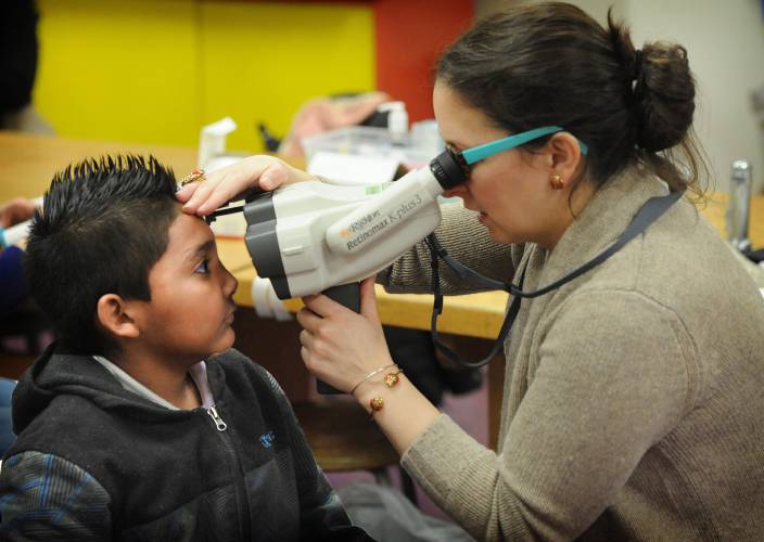 Dr. Megan Collins, right, a pediatric ophthalmologist at Johns Hopkins Hospital, gives a vision screening to third-grader Alexander Dominguez. 