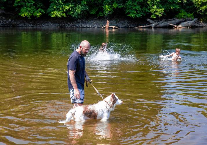 Nathan Lamere and his dog Dexter keep an eye on his son, Jonathan, and daughter Nateleigh, as they wades in the Merrimack River at Riverland Beach in Canterbury on Tuesday, June 18, 2024 as the tempertures started to rise in the area.