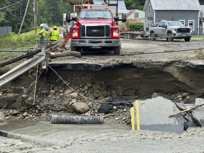 A crew works on a damaged roadway after flooding in Lyndonville, Vt., Tuesday, July 30, 2024. (AP Photo/Nick Perry)