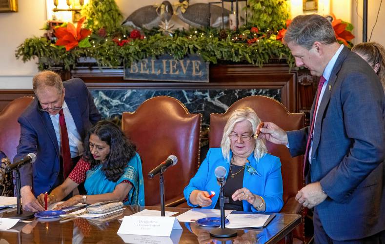 Governor Chris Sununu and Secretary of State David Scanlan help Electors Latha Mangipudi, and Eva Castillo-Turgeon seal with wax their documents for the four electors cast ballots on behalf of Vice President Kamala Harris and Minnesota Gov. Tim Walz, the Democratic vice presidential nominee, in a ceremonial vote at the Executive Council chamber on Tuesday, December 17, 2024.