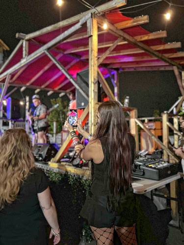 Starsea Deoss, who organizes emo nights around Concord, films a band at the “Summertime Sadness” concert.