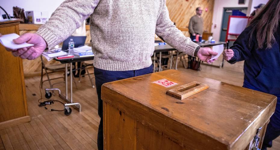 Pembroke town moderator Tom Serafin receives votes in both hands as voters cast their ballot on the first warrant article on Saturday.