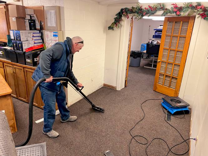 Robert Stewart, owner of All Brite Cleaning & Restoration of Gilford and Concord, vacuums some of the waterlogged carpet inside the facilities center of Plymouth State University on Wednesday after the flood receded and they were able to start cleaning the offices.