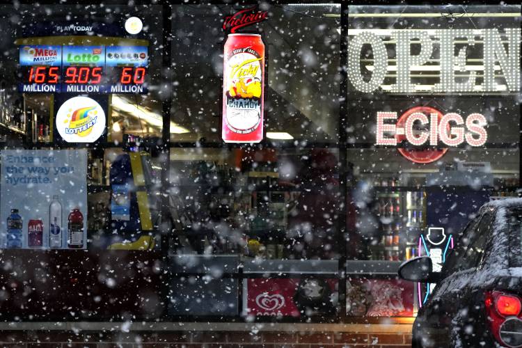 Snow falls down outside of a grocery store in Wheeling, Ill., Tuesday, Jan. 9, 2024. (AP Photo/Nam Y. Huh)