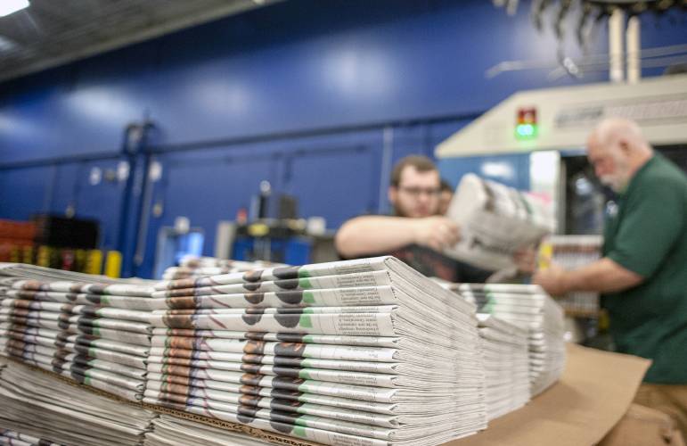 In this April 11, 2018, photo, production workers stack newspapers onto a cart at the Janesville Gazette Printing & Distribution plant in Janesville, Wis. Members of Congress are warning that newspapers in their home states are in danger of cutting coverage or going out of business if the United States maintains recently imposed tariffs on Canadian newsprint.  (Angela Major/The Janesville Gazette via AP)