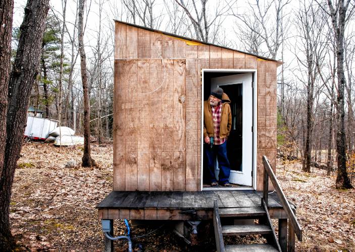 Woodworker David Emerson peaks out of the tiny house he is modeling on his Canterbury property on March 12.