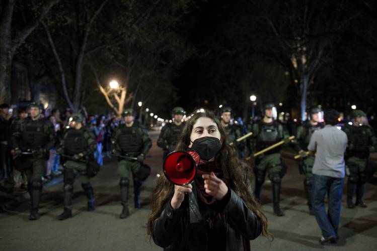 Dartmouth College student and activist Roan Wade attempts to tell student protesters to disperse and remain safe as New Hampshire State Police in riot gear move down North Main Street in Hanover, N.H., clearing the road after hours of protests on Wednesday.