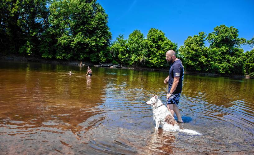 Nathan Lamere and his dog Dexter keep an eye on his son, Jonathan, and daughter Nateleigh, as they wades in the Merrimack River at Riverland Beach in Canterbury on Tuesday, June 18, 2024 as the tempertures started to rise in the area.