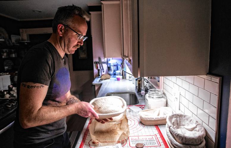 Alex Brown gets ready to put the dough for his bread into the oven at his South End home. Brown is getting a new bread oven to increase his weekly output.