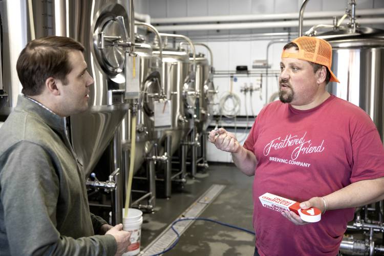 Tucker Jadczak, owner of Feathered Friend Brewing Co., shows U.S. Rep. Chris Pappas the beer tap handle and aluminum that he ordered from Canada where he received a $750 tariff bill last week.