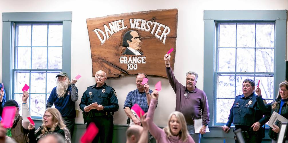 Webster residents raise their voting cards to pass an article on the warrant on Saturday, March, 16, 2024.