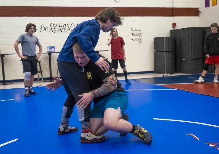 John Stark wrestling coach Zach Feudner instructs the team in the school cafeteria using wrestler Stephen Johnston on Jan. 24. The Generals finished third in Division III last season after finishing ninth in 2021-22 and are eager to keep that momentum up this season.
