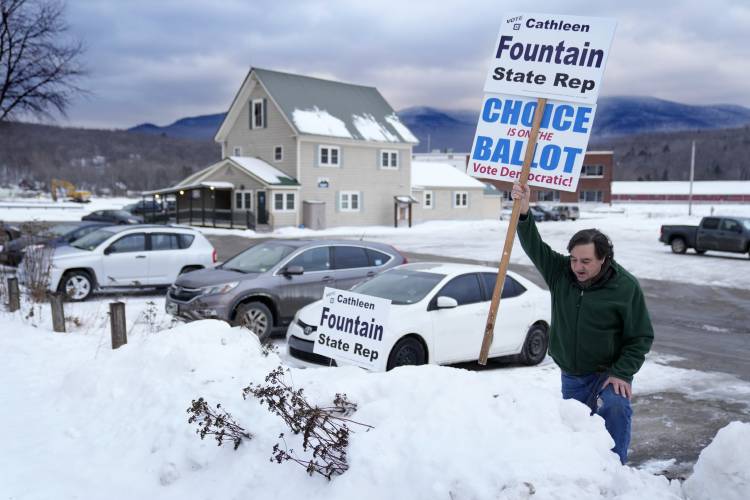 Joe Keenan plants a campaign sign in a snowbank outside Groveton village polling place, Tuesday, Jan. 23, 2024, in Northumberland, N.H. Local voters were electing a new state representative in addition to voting in the presidential primary election. (AP Photo/Robert F. Bukaty)