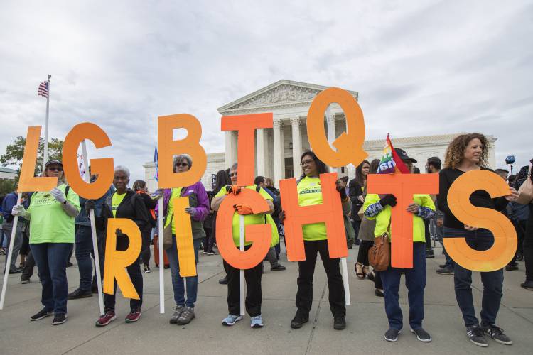 In this Oct. 8, 2019 photo, supporters of LGBTQ rights hold placards in front of the U.S. Supreme Court in Washington. In this Oct. 8, 2019 photo, supporters of LGBTQ rights hold placards in front of the U.S. Supreme Court in Washington.