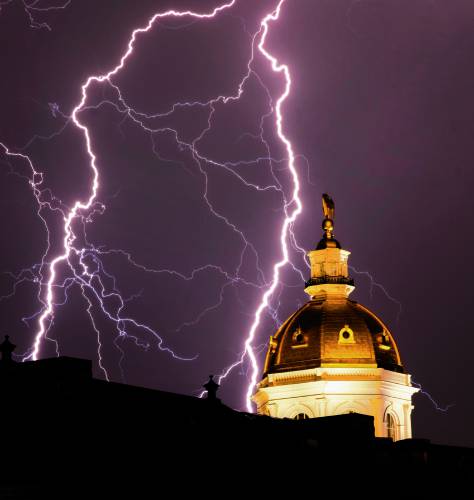 Lightning strikes near the east side of the New Hampshire State House as a front moved through the area on Tuesday night, July 16, 2024. The roof of the State Library is in the foreground.