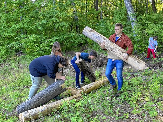Tim Lamendola and some of his advisory students carry out logs as part of their work to clear the trail behind Belmont Middle School.