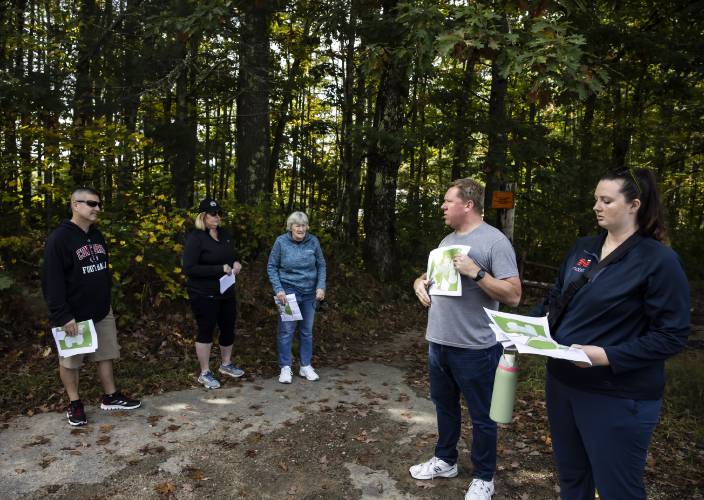 Jack Dunn, the SAU 8 business administrator, and Norbis project engineer Morgan Dunson use a map to show the participants of the middle school site tour the area as they stand at the trailhead which would be near the new school.