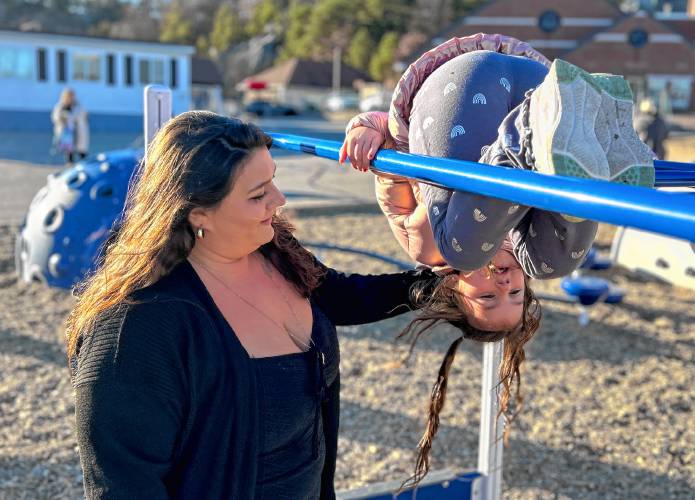 Haley Dempsey, 29, plays with her daughter, Sophia, 5, on the monkey bars at Sophia’s Manchester elementary school on a recent Wednesday afternoon.