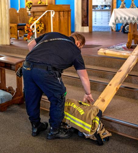 Allenstown firefighter/AEMT Ben Savage bows down to pick up the firefighter uniform at St. John the Baptist Catholic Church during the 9/11 Remembrance on Wednesday, Sept  11th, 2024. Besides the short service, Savage helped ring the electronic bells at the church at 9:03 to commerate the terrorist attack 23 years ago.

