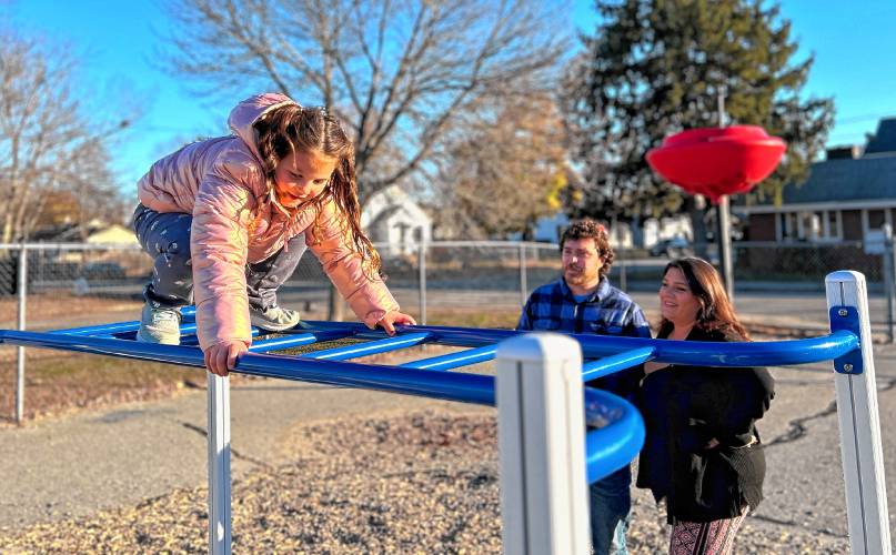 Haley and Connor Dempsey look on as their daughter, Sophia, 5, traverses the monkey bars outside her school on a recent Wednesday afternoon.