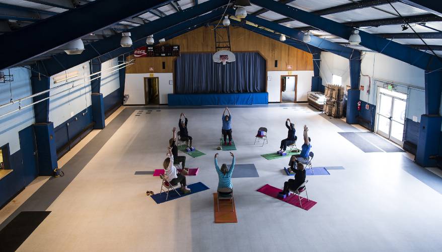 Instructor Kristina Lucas and students stretch as they begin their Gentle Yoga class at the Bow Community Center on Monday, June 4, 2018.