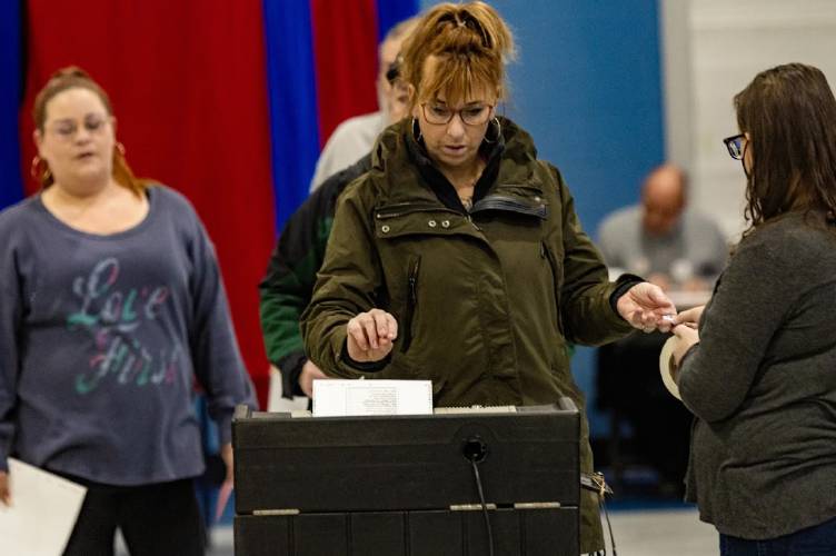 A voter submits her ballot into the ballot machine at the Bishop Leo E. O’Neil Youth Center in Manchester.