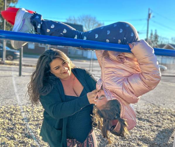 Haley Dempsey, 29, plays with her daughter, Sophia, 5, on the monkey bars at Sophia’s Manchester elementary school on a recent Wednesday afternoon.