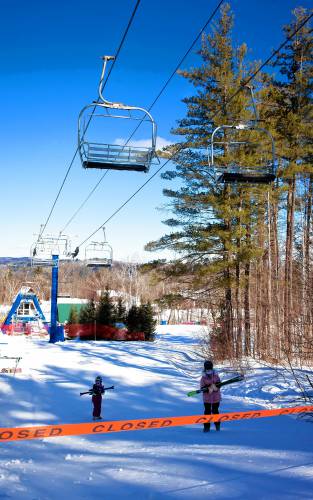 Skiers at Pats Peak carry their skies up the closed trail leading to the Peak Triple chair lift on Tuesday, February 18, 2025. The lift was still closed after Monday’s detachment due to high winds in the area.