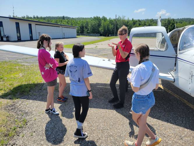 Pilot Karen Mitchell explains airplane control surfaces to young women at ACE Academy. Pilot Karen Mitchell explains airplane control surfaces to young women at ACE Academy.