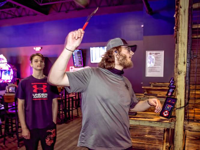 Isaiah Welch throws an axe at the Smitty’s Cinema and arcade area on Wednesday. Welch and his family came down from White River Junction for two days of movies and games.