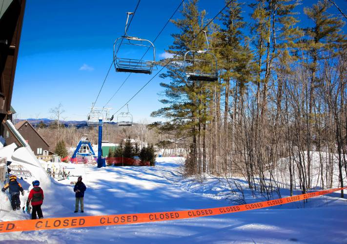 Skiers at Pats Peak carry their skies off the closed trail leading to the Peak Triple chair lift on Tuesday, Feb. 18. The lift was still closed after Monday’s detachment due to high winds in the area.