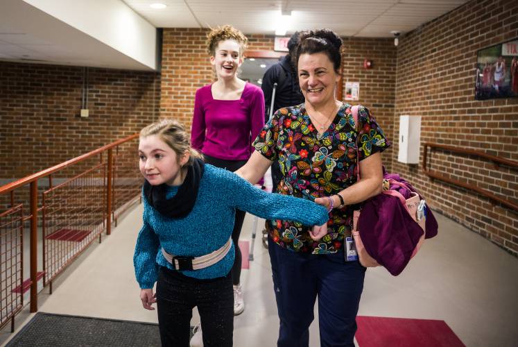 Izzie Boom is led through the hallways of Concord High School by her nurse, Lori Belanger, as her friend Emma Lesperance follows on April 3, 2025. They were on their way to meet Izzy’s mom at the main office.