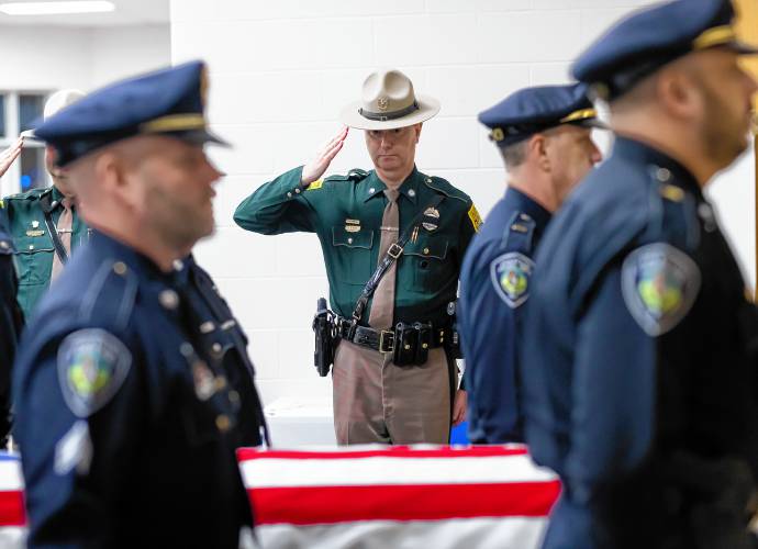 J.D. Rowe of  the New Hampshire State Police salutes as the casket of former Franklin Police Chief Bradley Haas enters the service in his honor at Winnisquam High School on Monday.