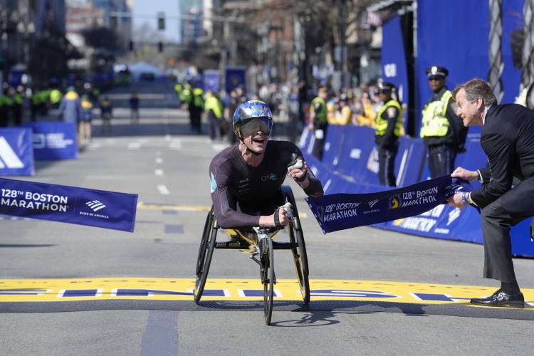 Marcel Hug, of Switzerland, breaks the tape to win the men's wheelchair division of the Boston Marathon, Monday, April 15, 2024, in Boston. (AP Photo/Steven Senne)