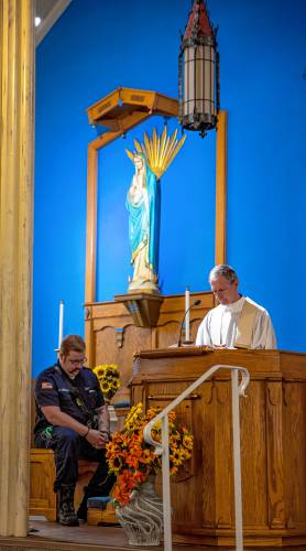 Allenstown firefighter/AEMT Ben Savage  bows in prayer as he listens to Rev. Michael Gendron of St. John the Baptist Catholic Church during the 9/11 Remembrance on Wednesday, Sept  11th, 2024. Besides the short service, Savage helped ring the electronic bells at the church at 9:03 to commerate the terrorist attack 23 years ago.

