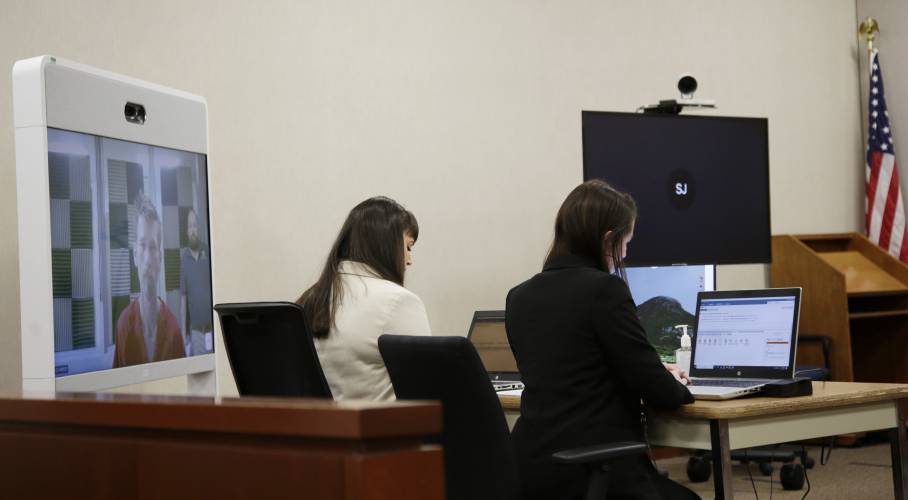 Jason Eaton is seen on a monitor, left, set up in the Burlington, Vt., courtroom where he was being arraigned Monday, Nov. 27, 2023. Eaton allegedly shot three college students of Palestinian descent, wounding them in what authorities said may have been a hate crime. (AP Photo/Hasan Jamali)