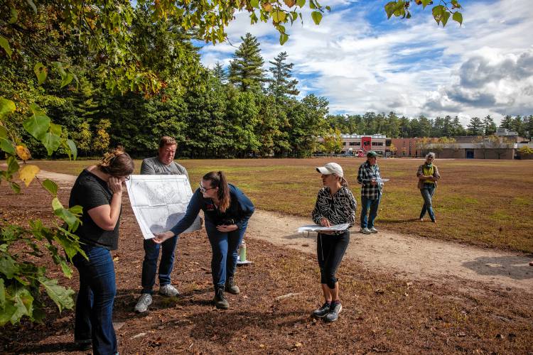 Norbis project engineer Morgan Dunson (center) shows maps as participants in the tour of the area proposed for the new middle school walk the area behind Mill Brook and Broken Ground schools on Saturday, September 28, 2024.